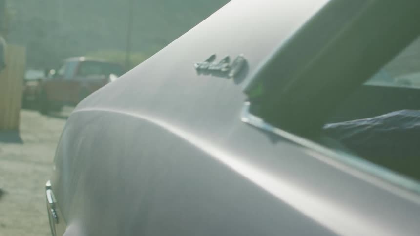 A man holding a water bottle standing near a car