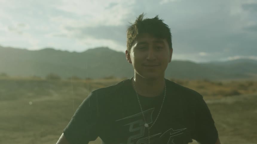 A young man is looking at the camera in the desert