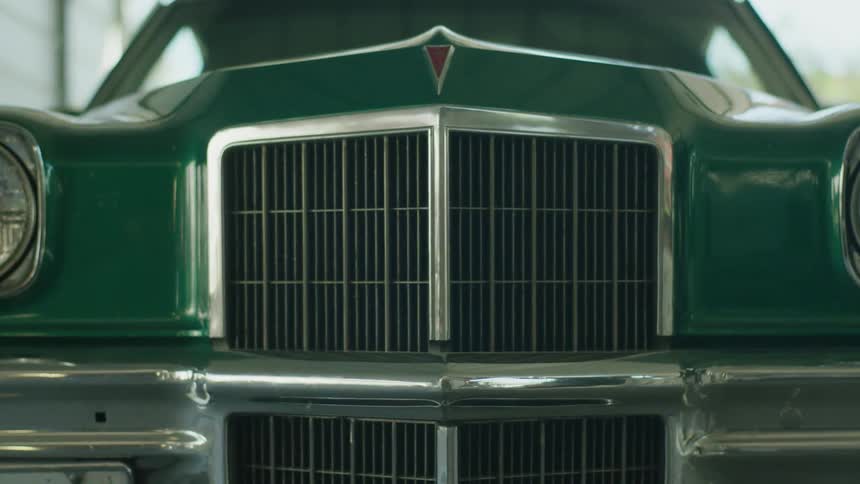 A person walks near a green car