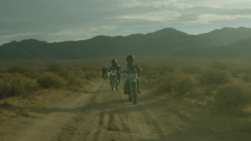 People ride off road vehicles on a dirt road