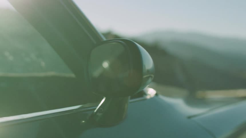 Man walks in front of parked car in the mountains