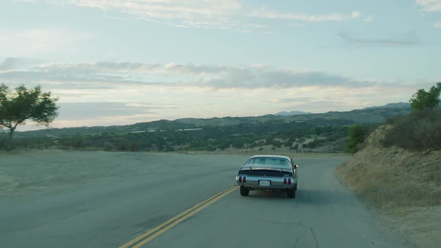An antique car is driven on a rural road