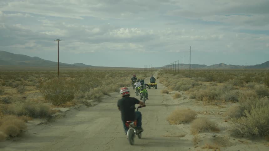 A group of dirt bikers are riding through the desert