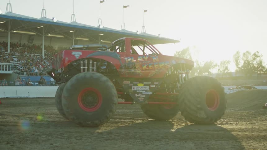 A crowd is watching a monster truck performance in a stadium