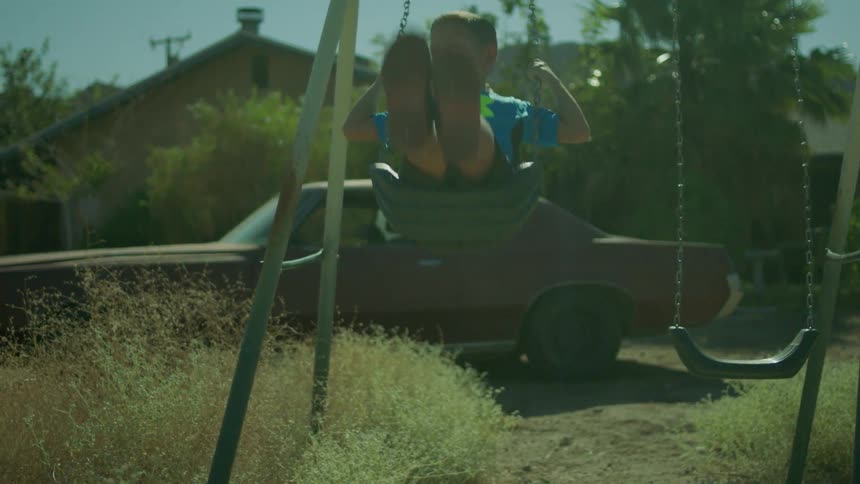 A child is swinging on a swing in a yard during the day