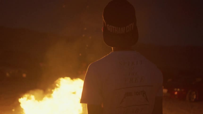 A boy is watching a bonfire burn at night
