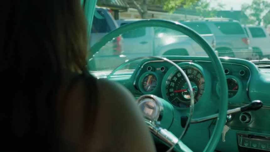 A woman drives a teal car