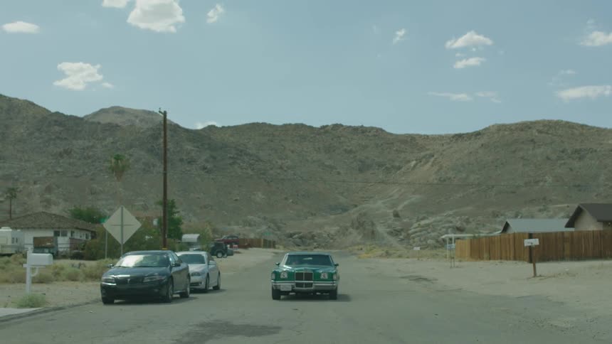 A teal hot rod parks on the side of the road