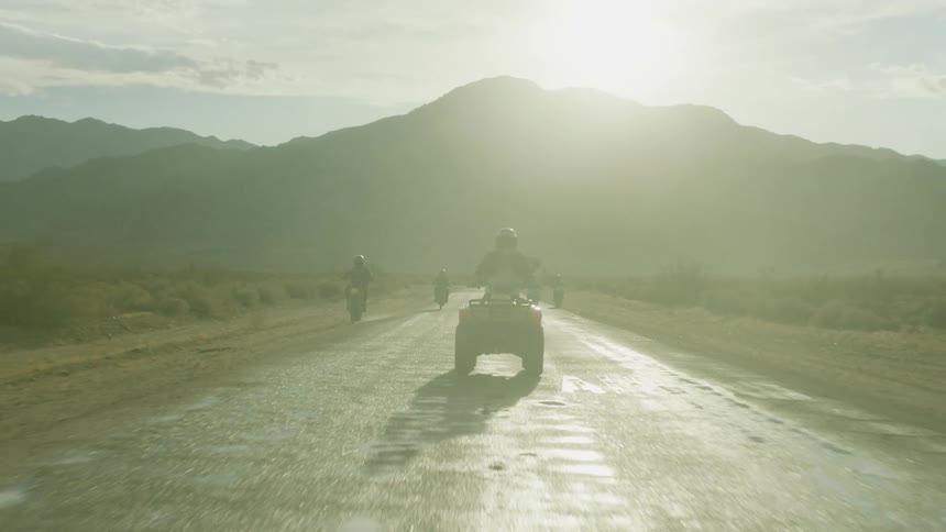 A group of bikers led by someone on a 4 wheeler