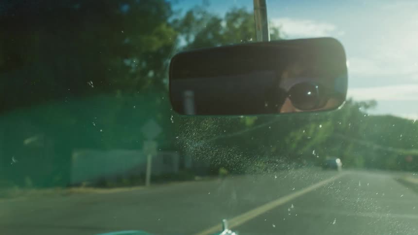 A car is driving down a road on a very sunny day