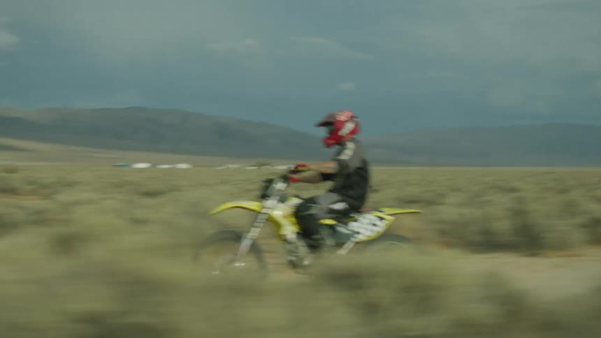 A dirt bike rider is riding a wheelie through the desert