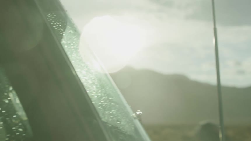 A truck sits parked outside with rain beading on the windshield