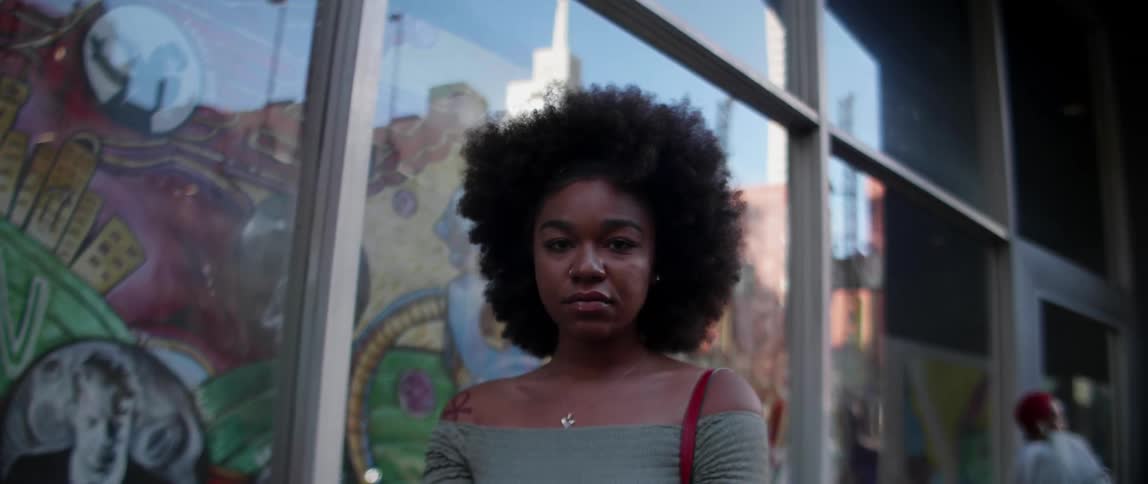A woman stands in front of window outside in the city during the day
