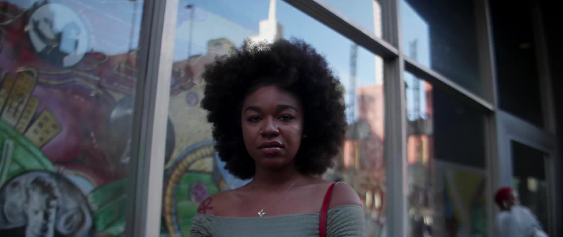 A woman stands outside of a big window that reflects city buildings
