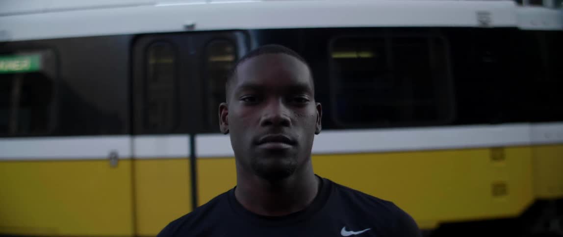 A black man stands in front of a trolley car