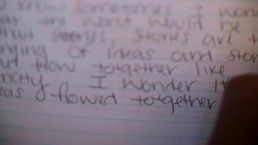 A person is writing using a pencil in a notebook
