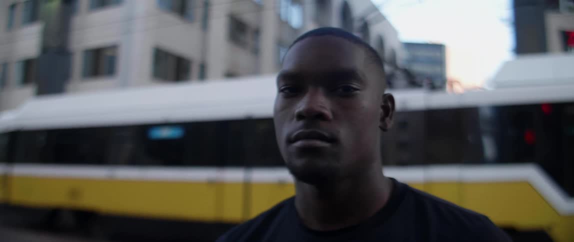A black man stands in front of a trolley car