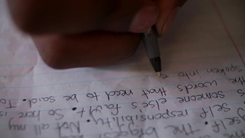 A person writes in a notebook with a pen