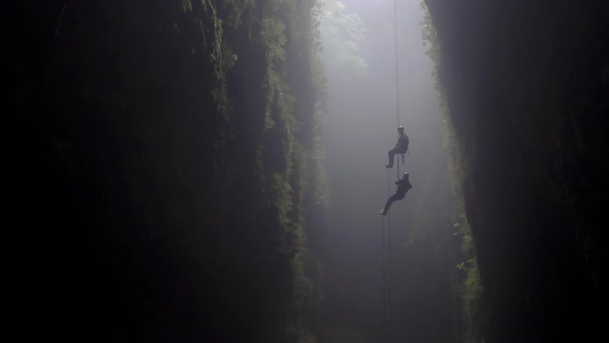 Two people cave dive into a cavern