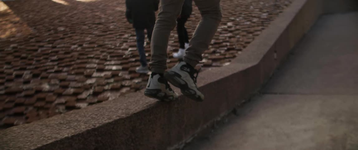 A person balances on the edge of a concrete walkway before jumping off