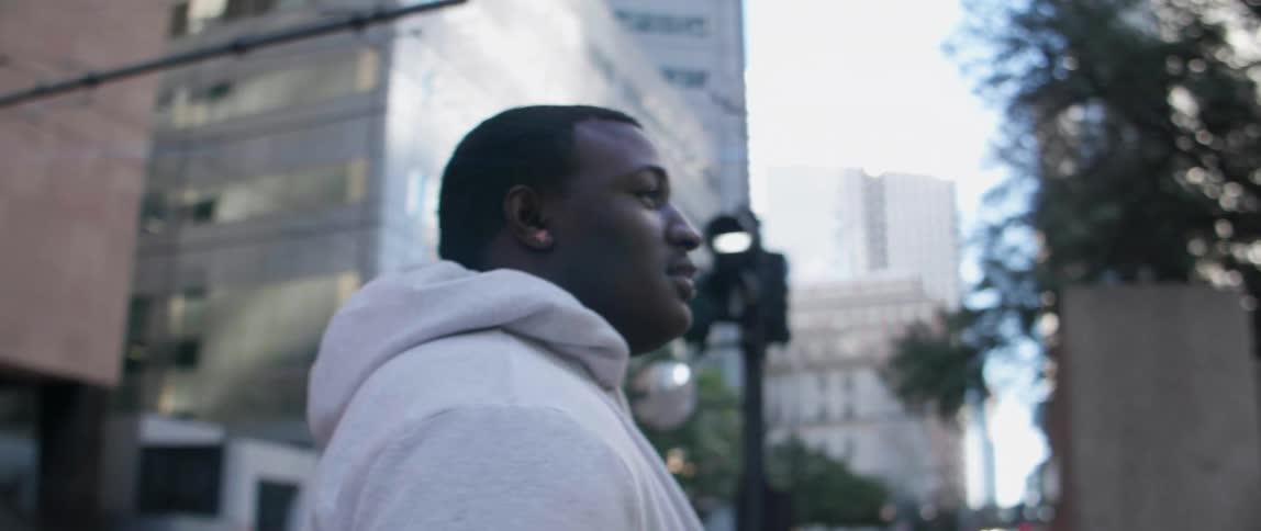 A man walks and looks up at buildings in the city
