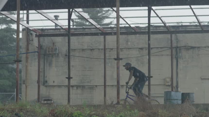 A man is riding his bicycle in the rain