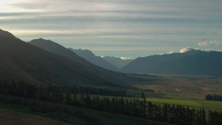 The sun shines on a rolling mountain landscape