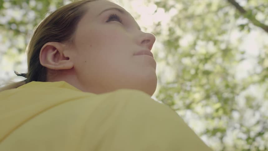 A woman stands in a sunny forested area