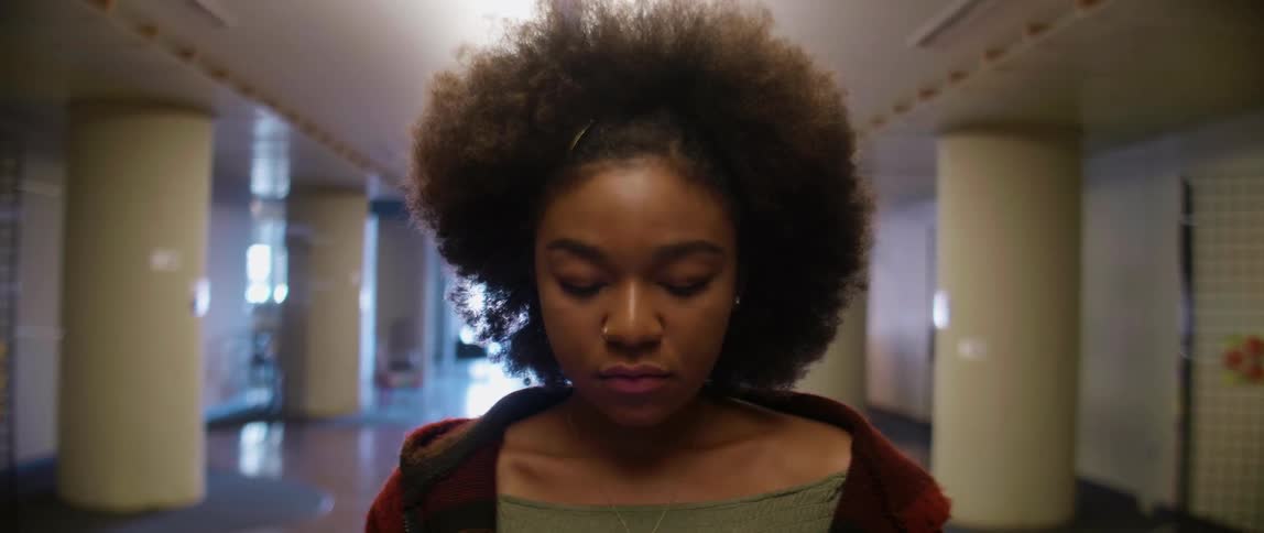 A woman is nodding her head as she stands in a hall