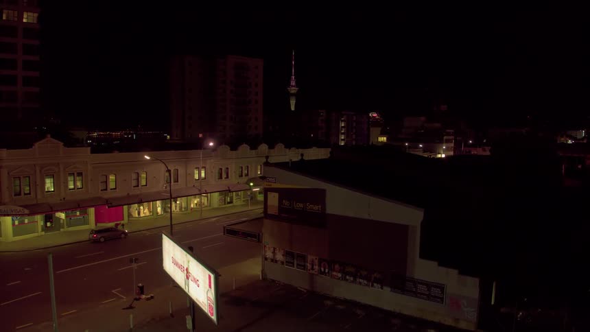 A few cars move along a city street at night