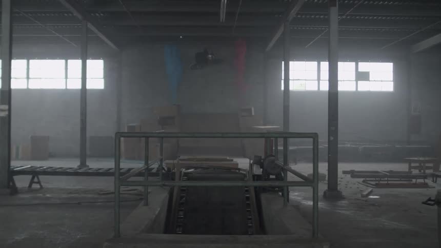 A person rides a bike over a ramp in a warehouse
