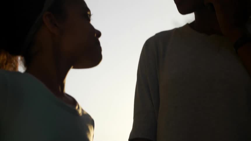 Young girl carrying a ball walks up to woman and briefly holds her hand