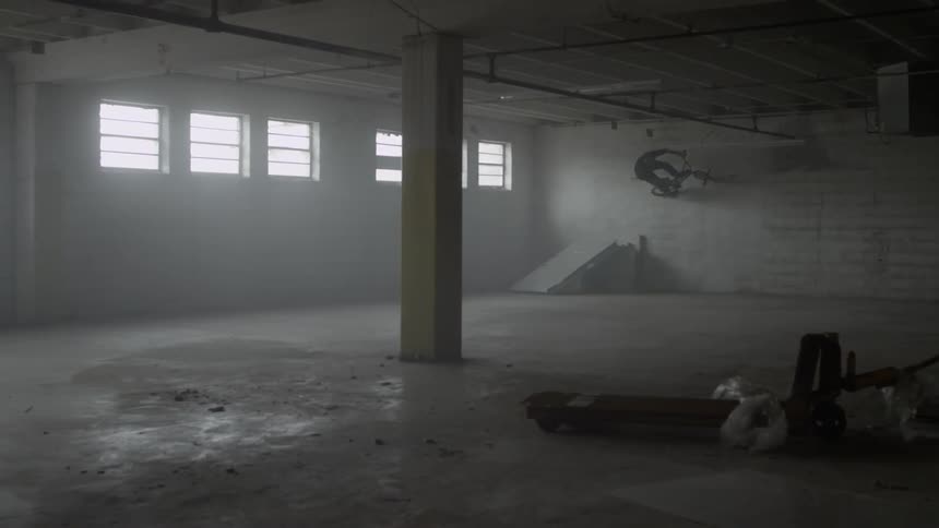 A man is riding a bicycle in an abandoned building during the day