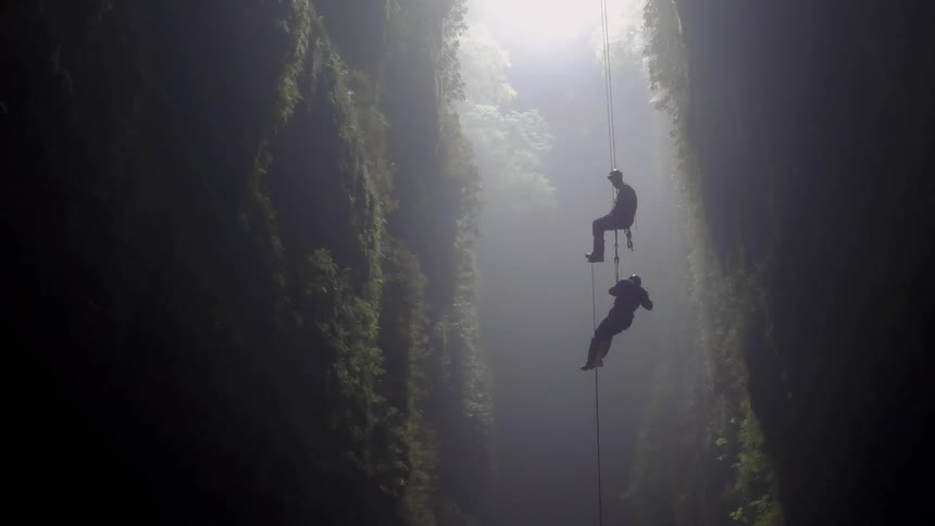 Two people cave dive into a cavern