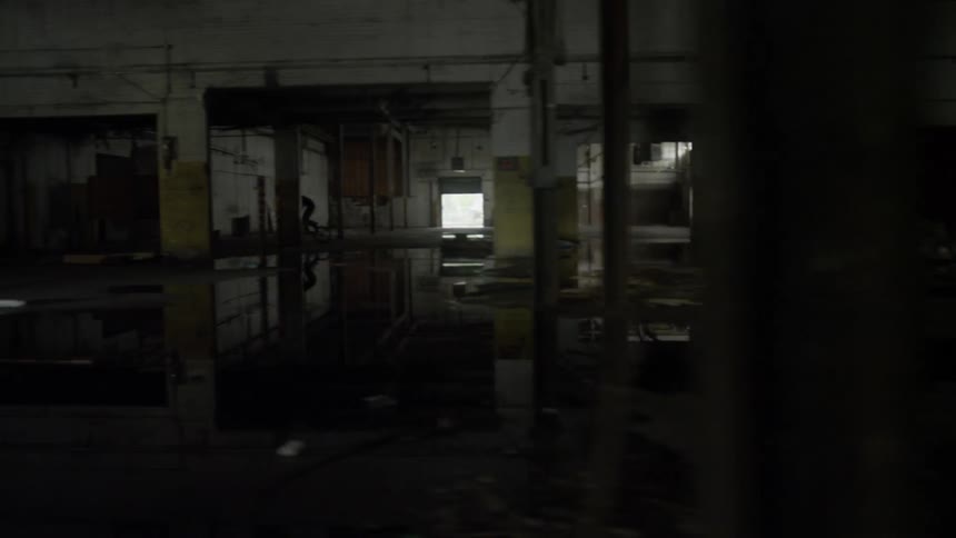 Someone is riding a bike really fast through an empty warehouse