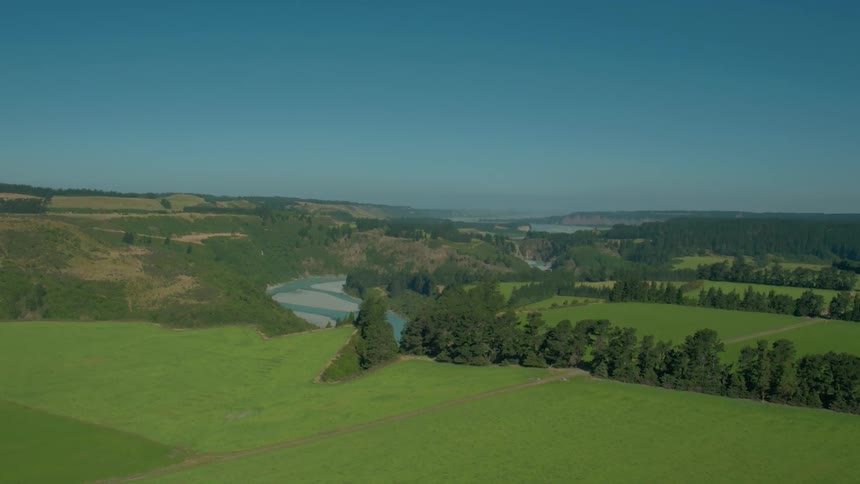 A long green field sits under the very clear sunny sky
