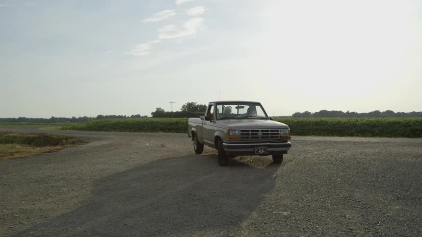 People sit in a parked pickup truck on a wide driveway
