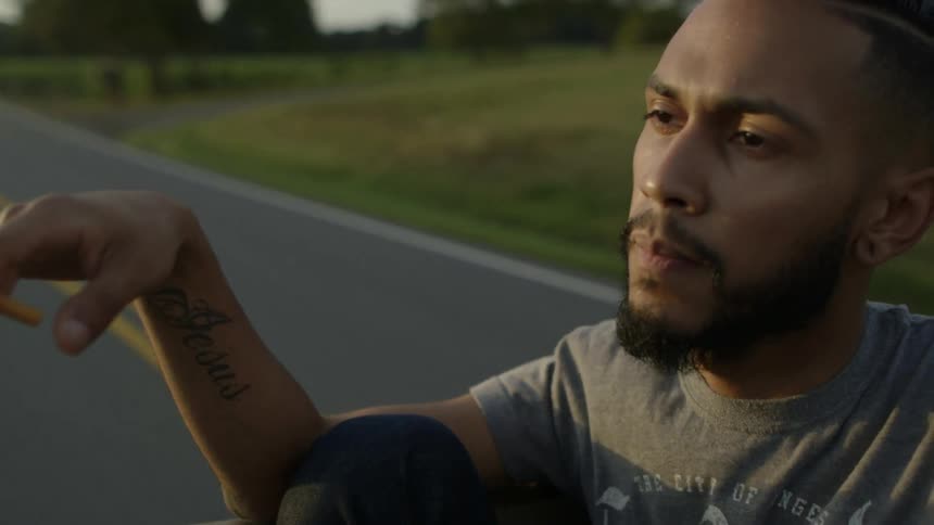 A man smokes in the back of a pickup truck
