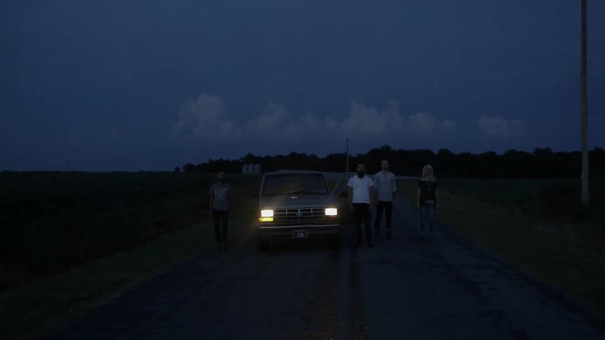 People stand next to parked truck in rural area