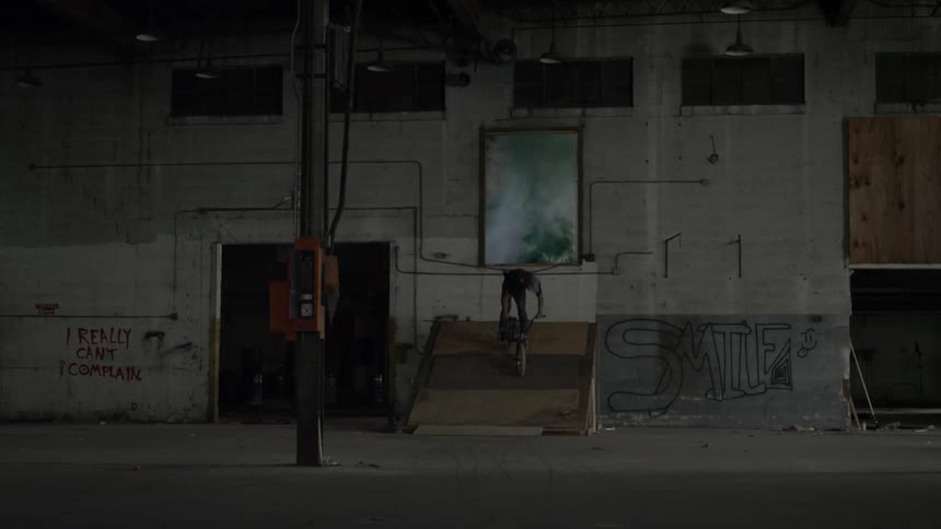 A person rides a bike through a smoky doorway
