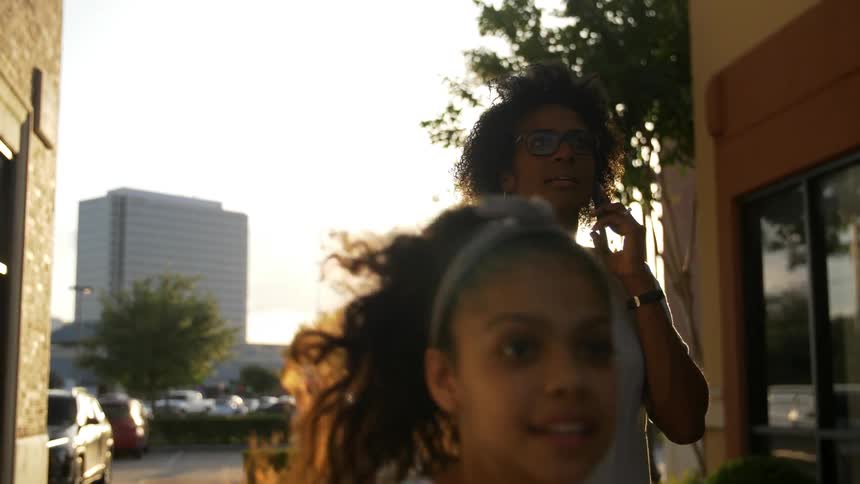A woman talking on the phone is pulled by a running girl