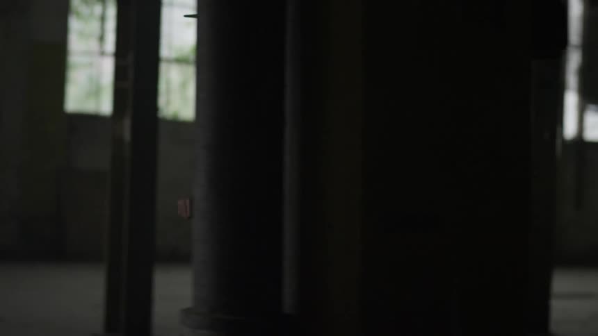A man rides a small bicycle in an abandoned warehouse
