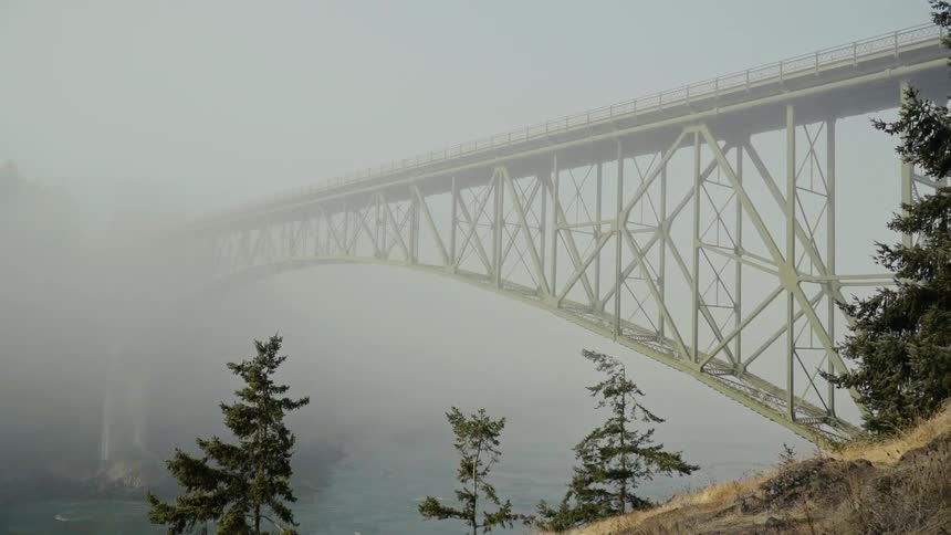 The bridge is completely covered with fog near the shore
