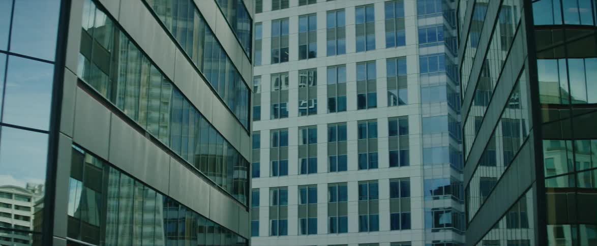 The glass windows of skyscrapers reflect a city during the day