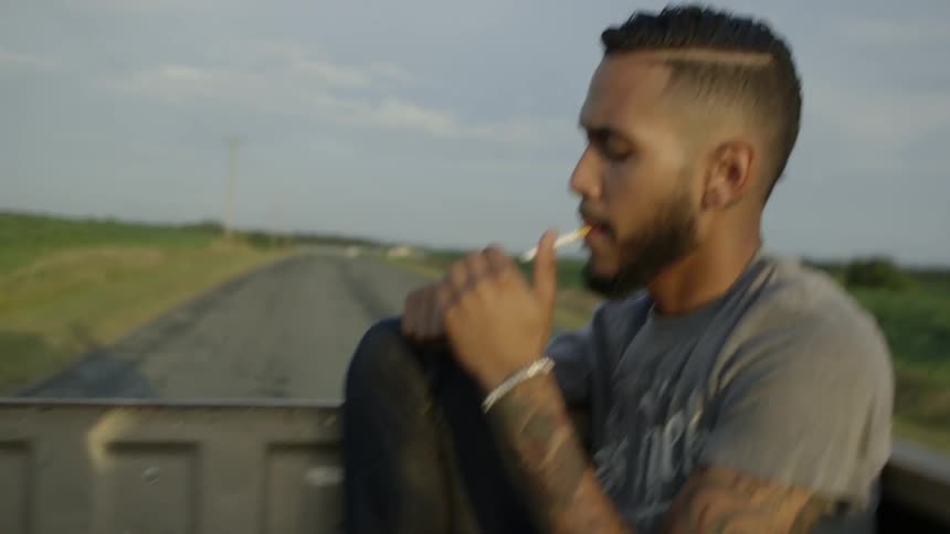 A man lights a cigarette in the back of a pickup truck