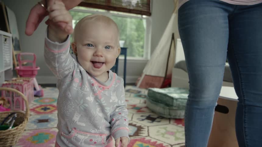 A woman walks a happy baby through the living room