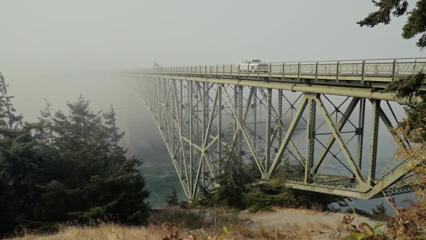 Vehicles travel over this fog covered bridge