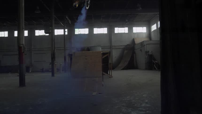 A man riding a bike in a warehouse does a backflip