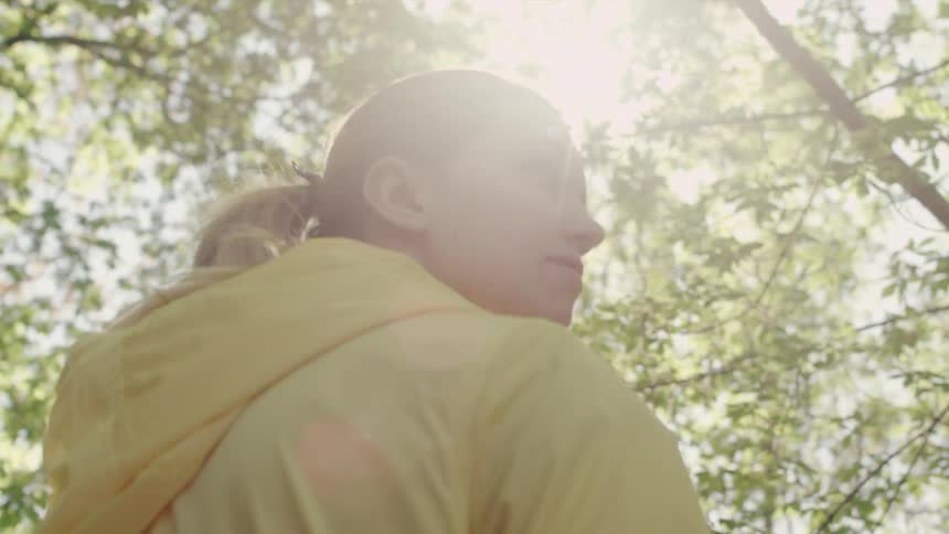 A woman is hiking outside in the woods smiling