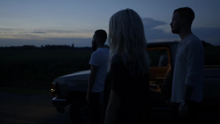 A group of people are standing by a car at dawn